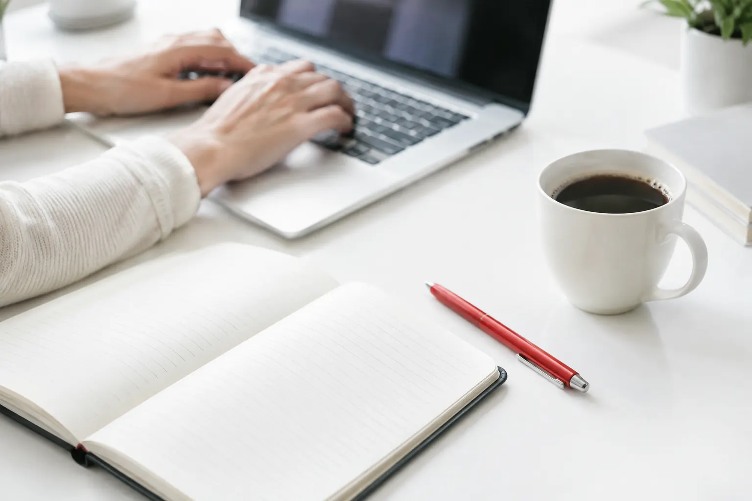 Mains sur un clavier près d’un carnet vierge : ce qu’il faut préparer avant de contacter un consultant SEO